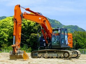 山を背景にしたオレンジ色の油圧ショベル